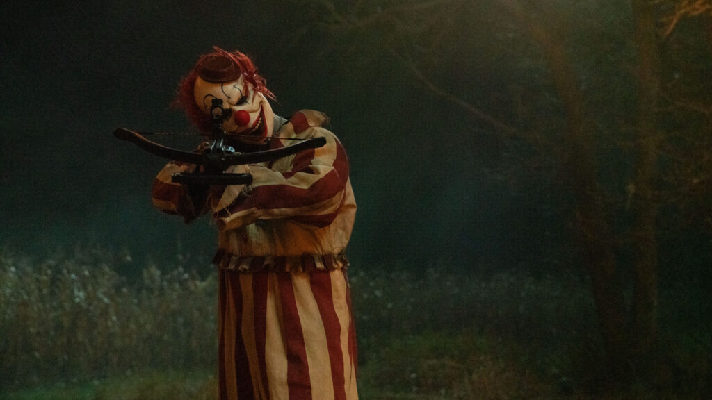 frendo the clown from clown in a cornfield holding a bow and arrow